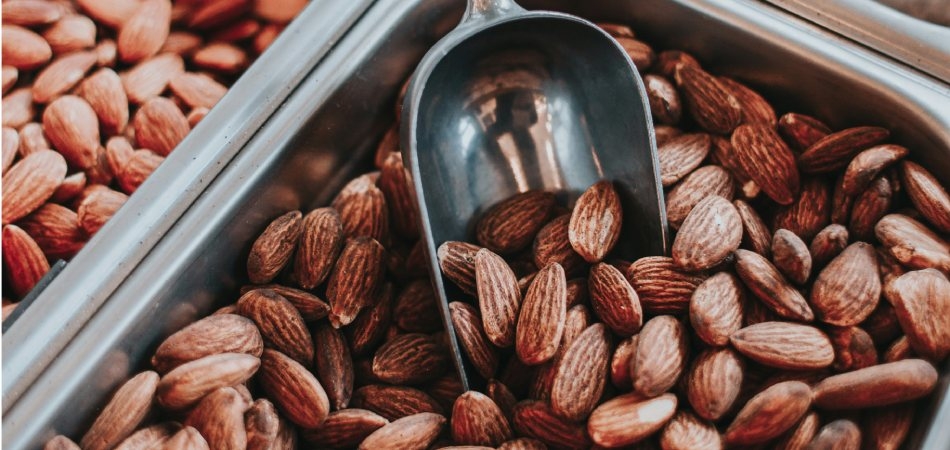 Een bak vol met gebrande amandelen en een metalen schep