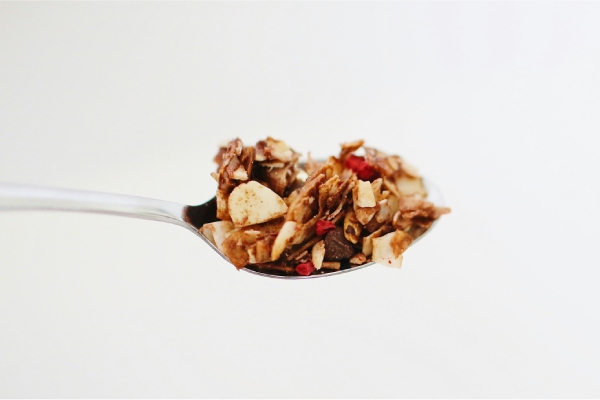 Granola vs. muesli: welke kies jij? een zilveren eetlepel gevuld met granola