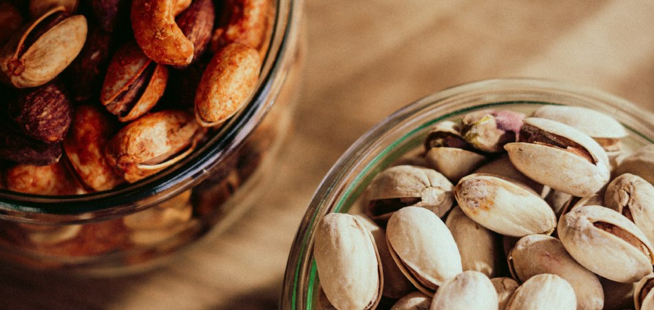 Hoelang kun je noten bewaren? Glazen potten met geroosterde en ongepelde pistachenoten