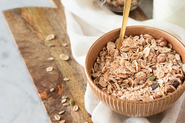 Een heerlijke kom granola als goede start van je dag een houten serveerplank met daarop een kom granola