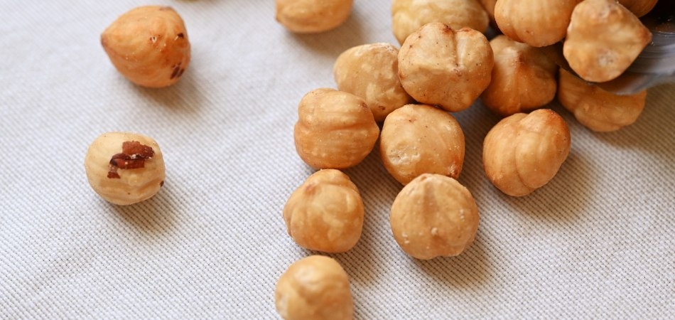 Een handvol ongebrande hazelnoten op een witte ondergrond